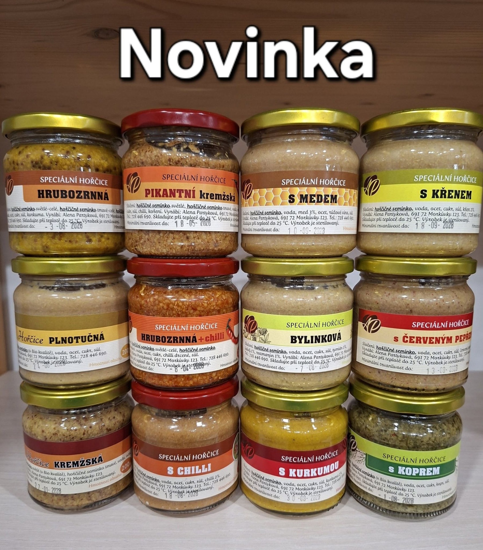 Sklenice speciálních hořčic s různými příchutěmi, na pozadí nápis „Novinka“.